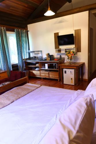 a bedroom with a bed and a flat screen tv at Aldeia Flor de Liz - Pedra Azul in Pedra Azul
