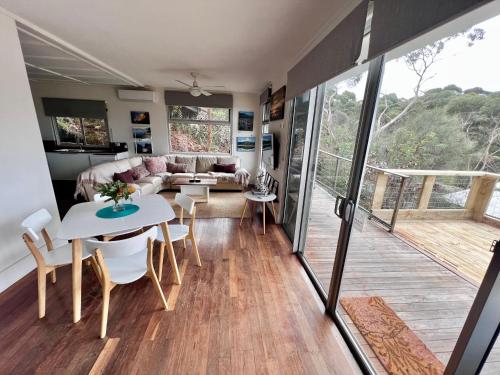 a living room and dining room with a table and chairs at Sunrise on Falie Seaview Eco Accommodation in American River