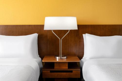 eine Lampe auf einem Nachttisch zwischen zwei Betten in der Unterkunft Garner Hotel Clarksville Northeast, an IHG Hotel in Clarksville