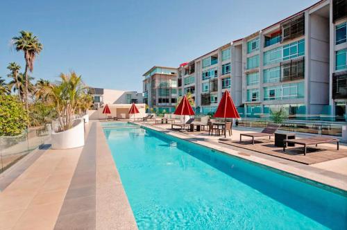 a swimming pool with tables and red umbrellas next to a building at Departamento en Nuevo Vallarta in Nuevo Vallarta