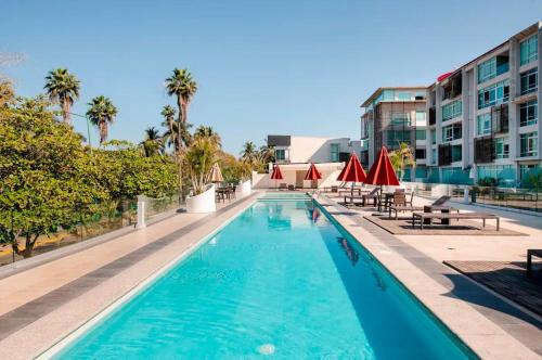 a pool at a hotel with tables and umbrellas at Departamento en Nuevo Vallarta in Nuevo Vallarta