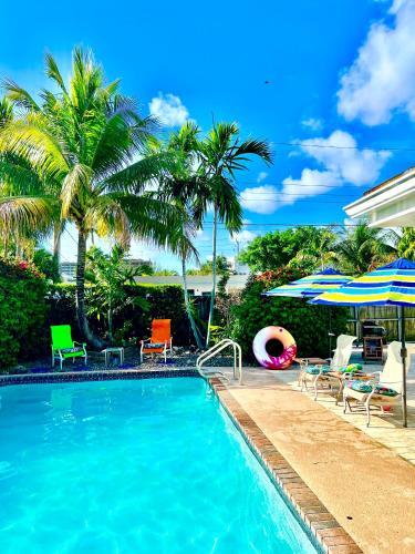 a swimming pool with chairs and umbrellas at Private Villa with Pool and Sauna in Dania Beach