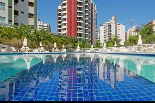 a large swimming pool with chairs and a building at Boulevard Riviera Flat in Riviera de São Lourenço