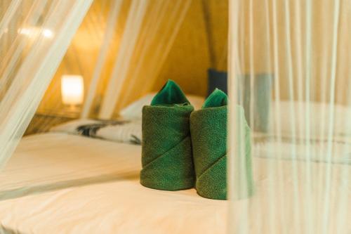 Duas almofadas verdes em cima de uma cama em Bamboo Bay Island Resort em Srithanu