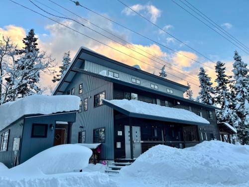 a house covered in snow with snow piled up at Bears Den Mountain Lodge in Hakuba