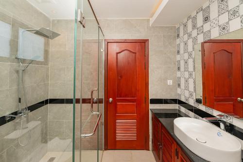a bathroom with a red door and a sink and a shower at Serenity Suites d'Angkor in Phumĭ Kântrák