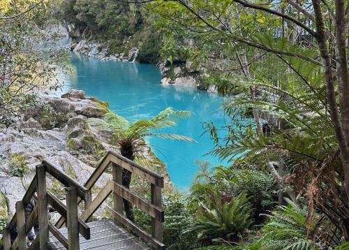a staircase leading down to a river with blue water at Drifting Sands Beachfront Retreat in Hokitika