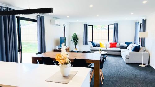 un salon avec un canapé et une table dans l'établissement Brand New House with 5 bedroom and 3 full bathroom, à Rotorua