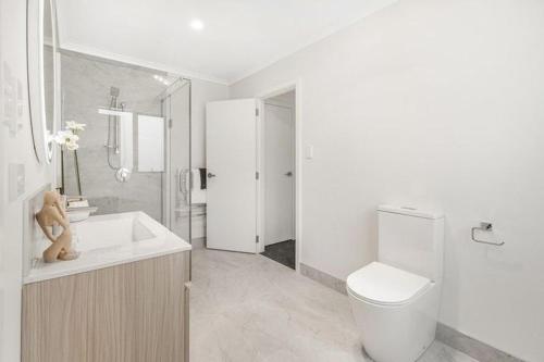 Baño blanco con aseo y lavamanos en Brand New House with 5 bedroom and 3 full bathroom, en Rotorua