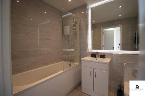 a bathroom with a tub and a sink and a shower at Newly Launched Two Bedroom House By Den Accommodation Short Lets & Serviced Accommodation With Garden in London
