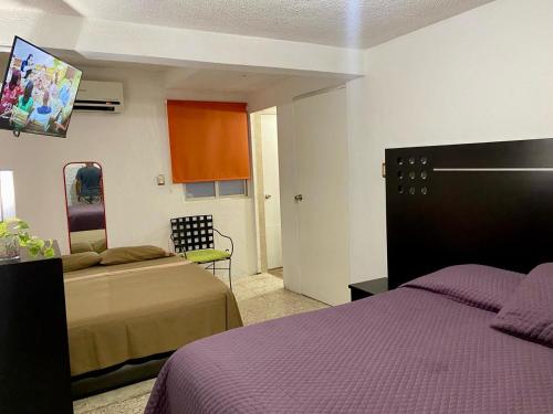 a hotel room with two beds and a chair at Casa Múkara del Puerto in Veracruz