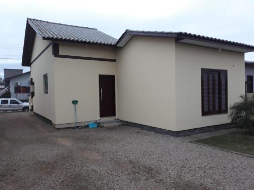 Uma casa branca com uma entrada à frente. em Casa Criciúma em Criciúma