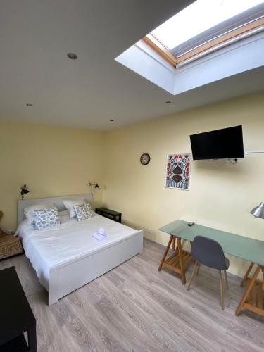 1 dormitorio con 1 cama, TV y escritorio en Logement Lumineux - Leuville-sur-Orge en Leuville-sur-Orge