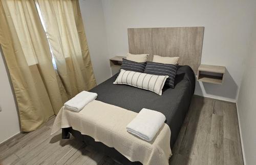 a bedroom with a large bed with two pillows at Complejo Chile Plottier in Plottier
