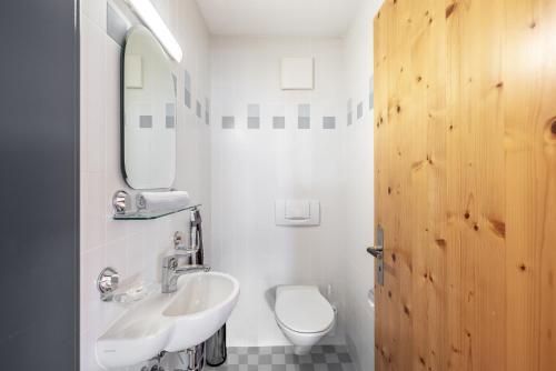 bagno con lavandino, servizi igienici e specchio di Alta Vista a Scuol