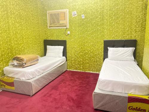 two beds in a room with a green wall at غرفة وحمام مكة العزيزية قريب الحرم in Al ‘Azīzīyah