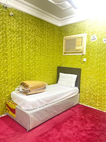 a bedroom with a bed with a green wall at غرفة وحمام مكة العزيزية قريب الحرم in Al ‘Azīzīyah