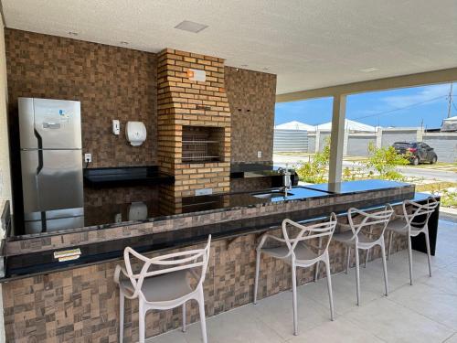 a kitchen with a counter with chairs and a refrigerator at Apto praia ponta de campina in Cabedelo