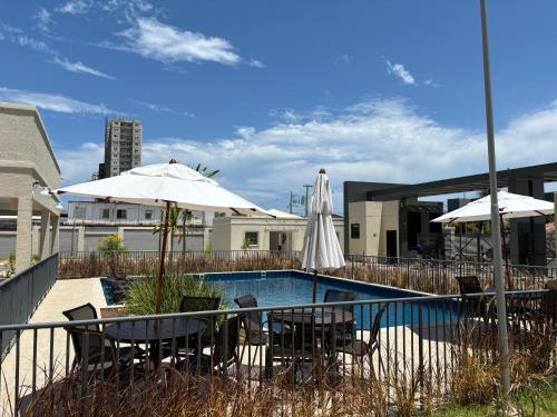 a pool with tables and chairs and umbrellas at Apto praia ponta de campina in Cabedelo