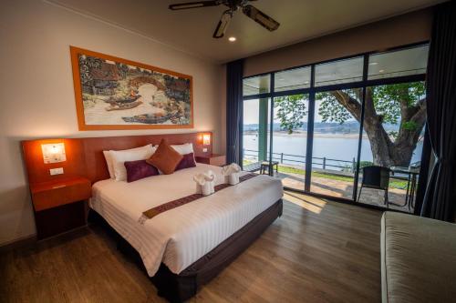 a bedroom with a large bed and a large window at Khong Chiam Orchid Riverside Resort in Khong Chiam