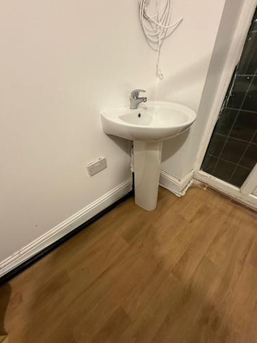 uma casa de banho com um lavatório branco e piso em madeira em Crete home em Oldham