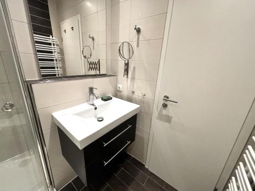 ein weißes Bad mit einem Waschbecken und einer Dusche in der Unterkunft Ferienpark Sierksdorf App 779 - Strandlage in Sierksdorf