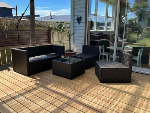 a patio with wicker furniture and a table and chairs at Kahu's Nest in Hokitika