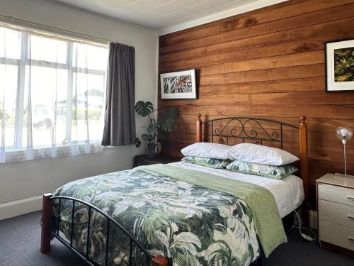 a bedroom with a bed with a wooden wall at Kahu's Nest in Hokitika