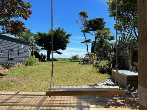 a porch with a wooden bench in a yard at Kahu's Nest in Hokitika