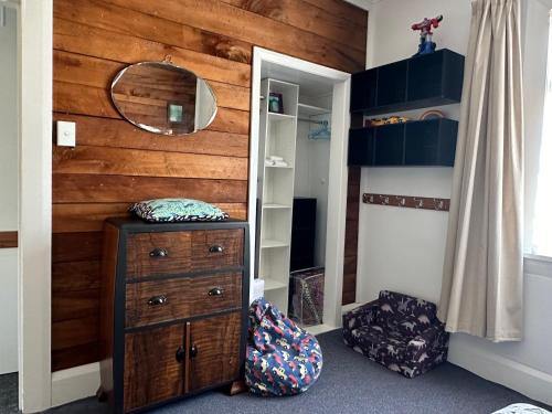 a bedroom with a wooden wall with a dresser and a mirror at Kahu's Nest in Hokitika