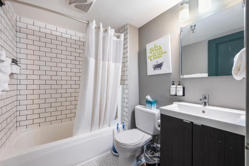a bathroom with a sink and a toilet and a bath tub at Oxford Apartment by At Mine Hospitality in Seattle