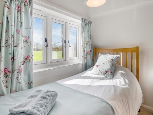 a bedroom with a bed and a window at Buttercup Cottage in Old Buckenham