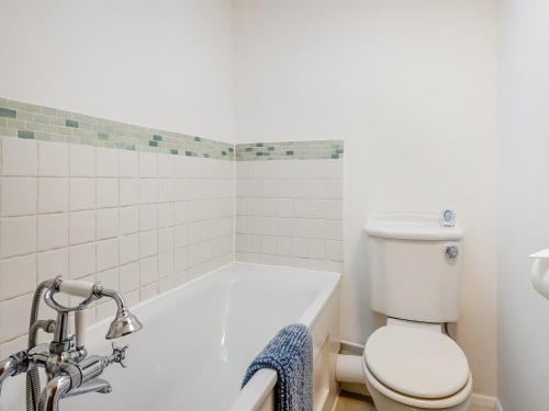 a bathroom with a toilet and a bath tub at Buttercup Cottage in Old Buckenham