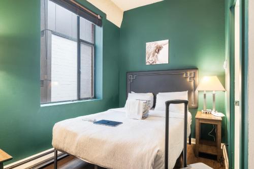 a bedroom with a bed with green walls and a window at Oxford Apartment by At Mine Hospitality in Seattle
