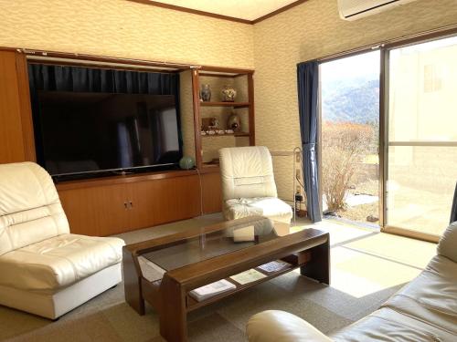 een woonkamer met 2 stoelen, een tafel en een tv bij Nikko World Heritage STAY【日光山内】一棟丸貸しの宿 in Nikko