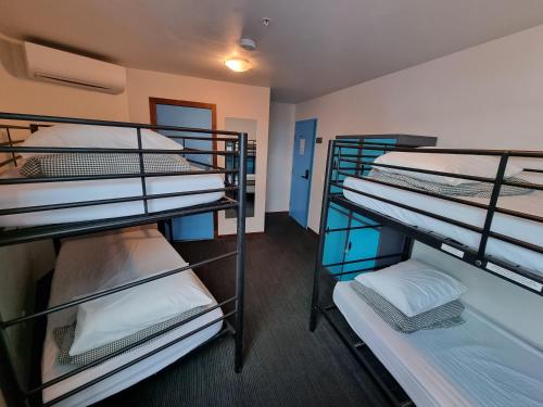 a room with three bunk beds in it at Nomads St Kilda in Melbourne