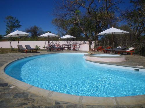 a large swimming pool with chairs and umbrellas at Hotel Lakana Ramena in Diego Suarez