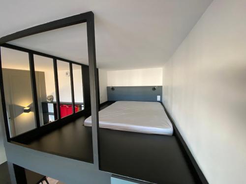 une petite chambre avec un lit et un miroir dans l'établissement Arcachon : studio duplex face plage, centre-ville, Wi-Fi, parking - FR-1-319-500, à Arcachon