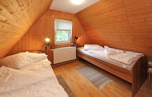 two beds in a room with wooden walls at Nice Home In Frstenhagen With Lake View in Fürstenhagen