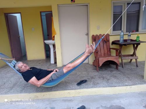 a man laying in a hammock in front of a house at Hostal The Friends in Panajachel