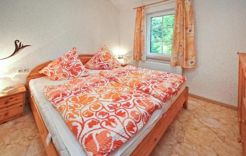 a bed with an orange and white comforter and a window at 3 Bedroom Beautiful Home In Thomsdorf in Thomsdorf