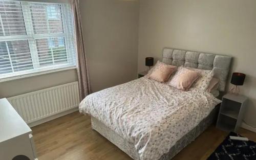 a bedroom with a bed with pink pillows and a window at Maidenhead house in Maidenhead