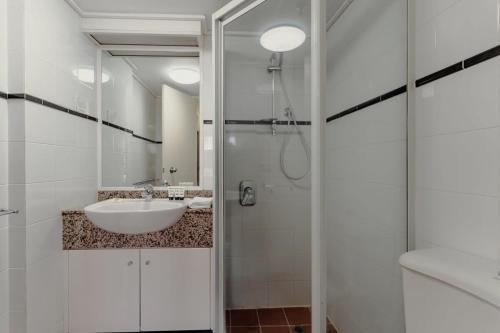 y baño blanco con lavabo y ducha. en 2-Bed with Gym, Tennis Court & Stunning Lake Views, en Canberra