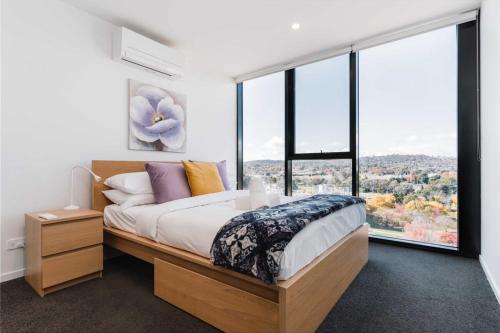 a bedroom with a bed and a large window at Lovely Sunny 2-bedroom Apartment with Pool and Gym in Phillip