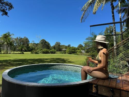 a woman in a bikini sitting next to a pool at Lake Weyba Cottages Noosa in Peregian Beach