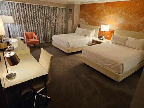 ラスベガスにあるExecutive Unit by Mandalay Casino at Strip Las Vegasのベッド2台とデスクが備わるホテルルームです。