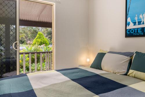 1 dormitorio con 1 cama y vistas a un balcón en Bon Villas B&B Bonville en Coffs Harbour