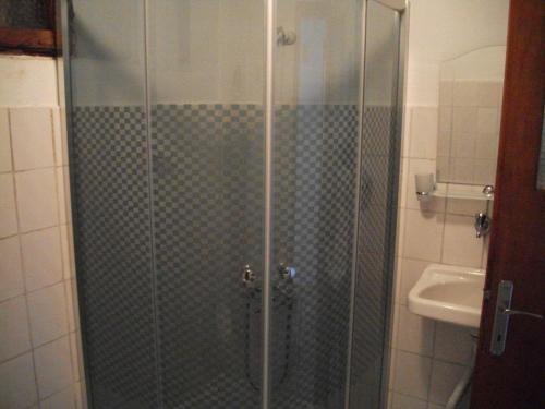ducha con puerta de cristal y lavamanos en Ernur Pension, en Canakkale