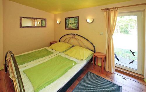 Un dormitorio con una cama con sábanas verdes y una ventana en 2 Bedroom Awesome Home In Rheinsberg Ot Zechline, en Scharfenberg