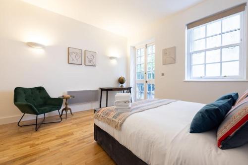 een slaapkamer met een bed, een stoel en een raam bij Wild Roses Serviced Apartments - Angel in Londen